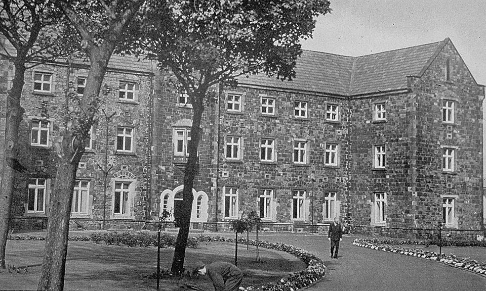 A black and white photograph of an old City Hospital building with trees in the foreground.