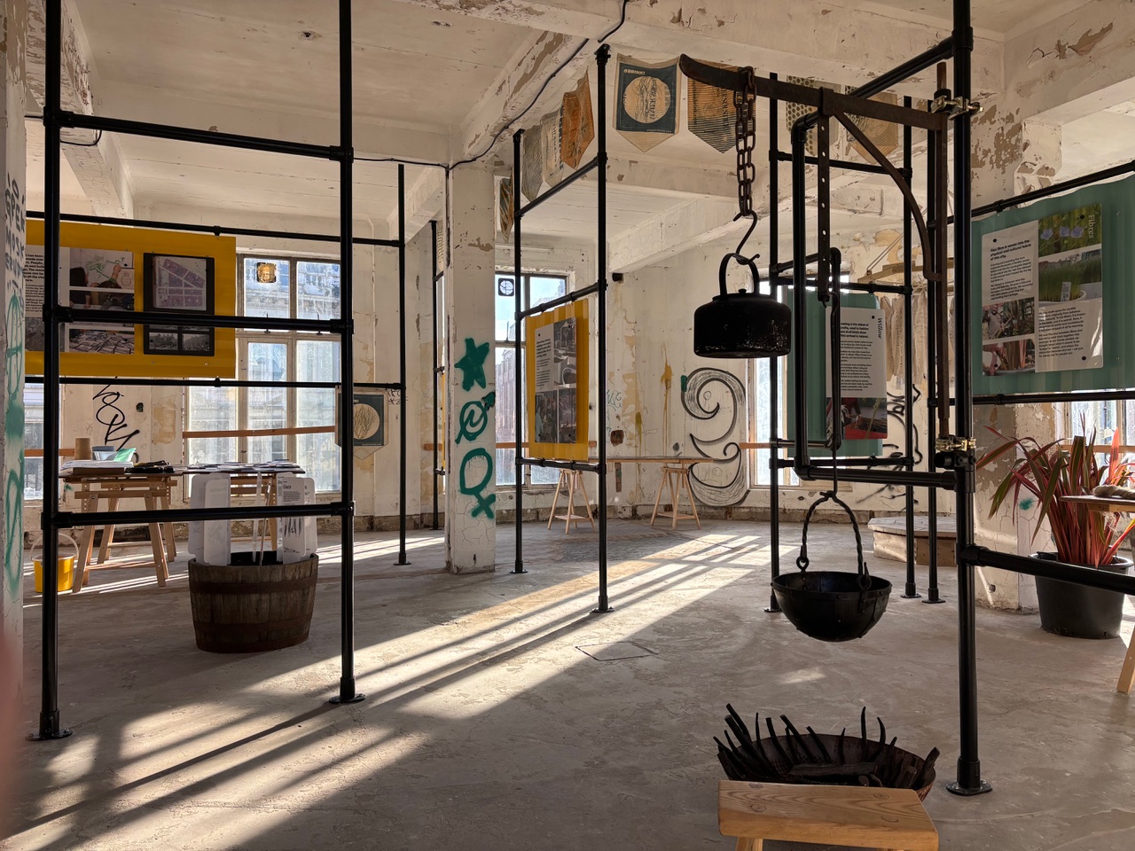 An exhibition in a run down building with rays of light shining through large windows