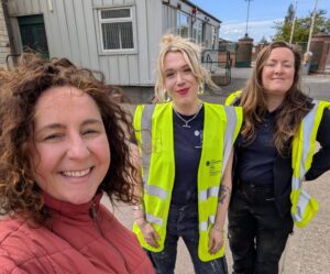 Jillian smiles at the front of the photo with 2 apprentices behind her in high vis yellow tops
